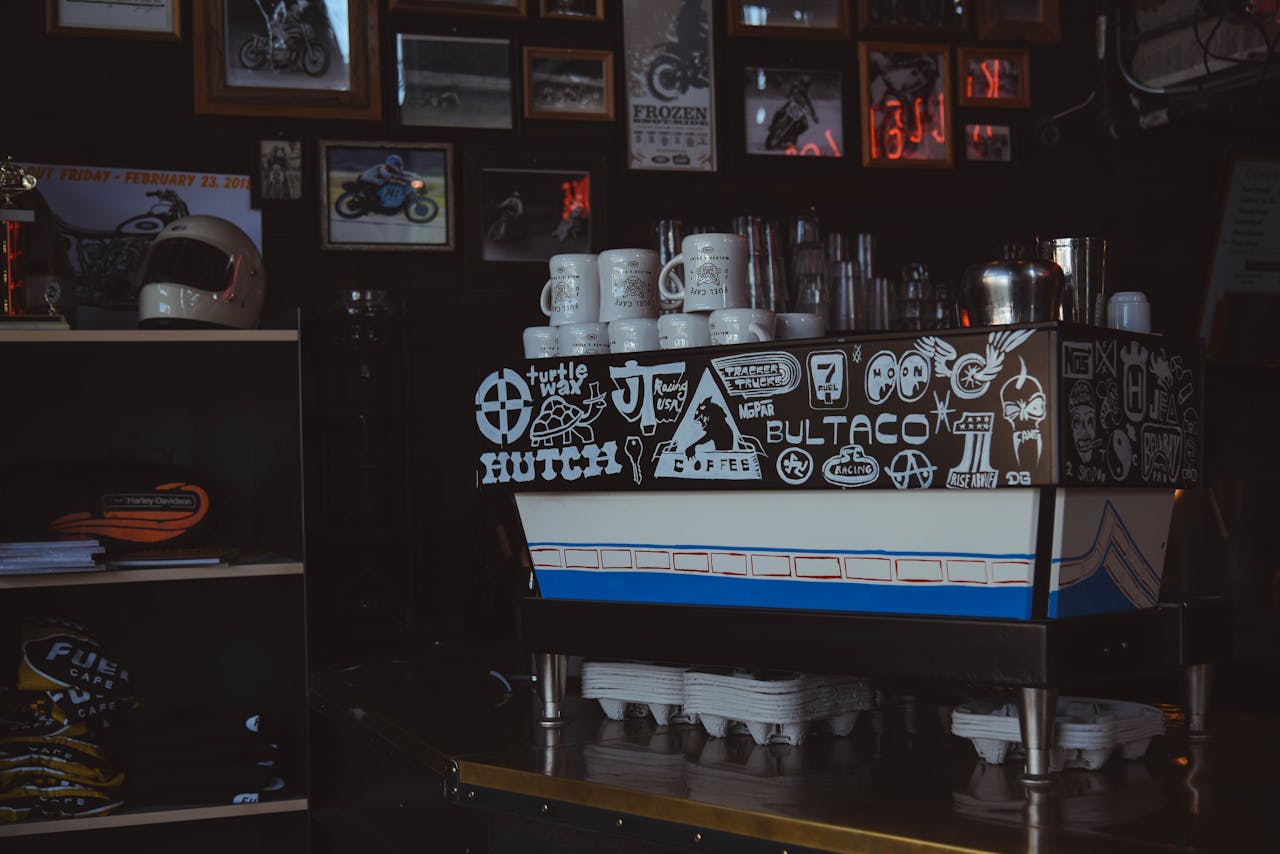 Stylish coffee shop interior featuring a creatively decorated espresso machine surrounded by retro motorcycle art.